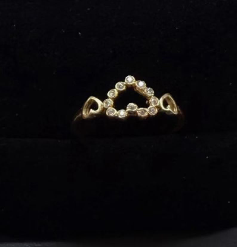 Gold ring with heart-shaped diamond design on a black background